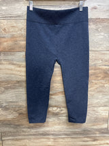 Front view of blue First Kick maternity leggings with high textured waistband and slim legs on wood background