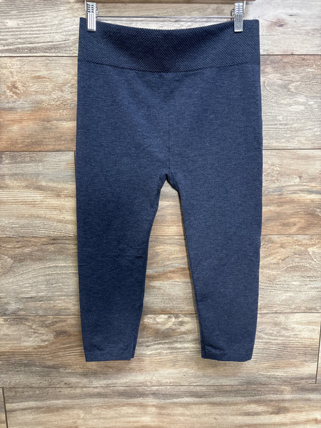 Front view of blue First Kick maternity leggings with high textured waistband and slim legs on wood background