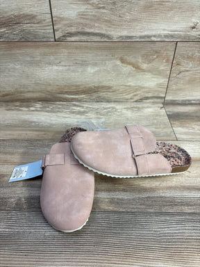 Pink suede slip-on clogs with floral printed insole and adjustable strap on wooden floor background