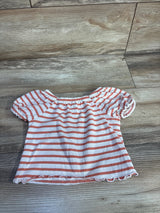 Flat-lay front of toddler puff-sleeve shirt in white with coral stripes, elasticized neckline and ruffled hem on wood floor