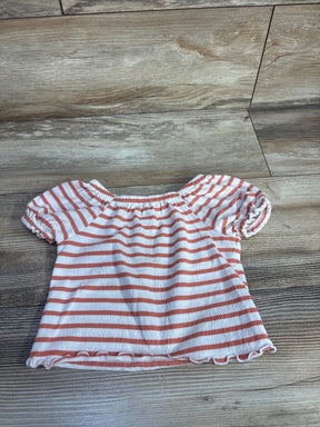 Flat-lay front of toddler puff-sleeve shirt in white with coral stripes, elasticized neckline and ruffled hem on wood floor