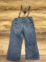 Rear view of H&M blue suspender jeans for 12 months showcasing two back pockets and adjustable suspenders on a wood background