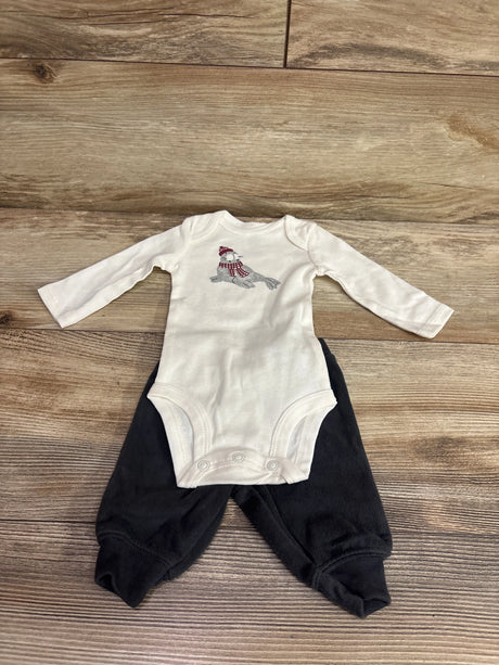 Flat lay of Just One You newborn bodysuit and pants set showcasing a seal graphic, white bodysuit, and black pants on wood
