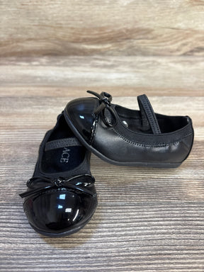 Black toddler dress shoes with bow detail on wooden surface