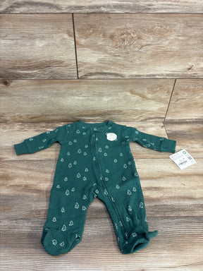 Green baby footed sleeper with white tree pattern and front zipper on wooden floor