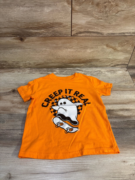 Flat lay of orange toddler tee size 4T showing Creep It Real ghost on skateboard graphic on wood background