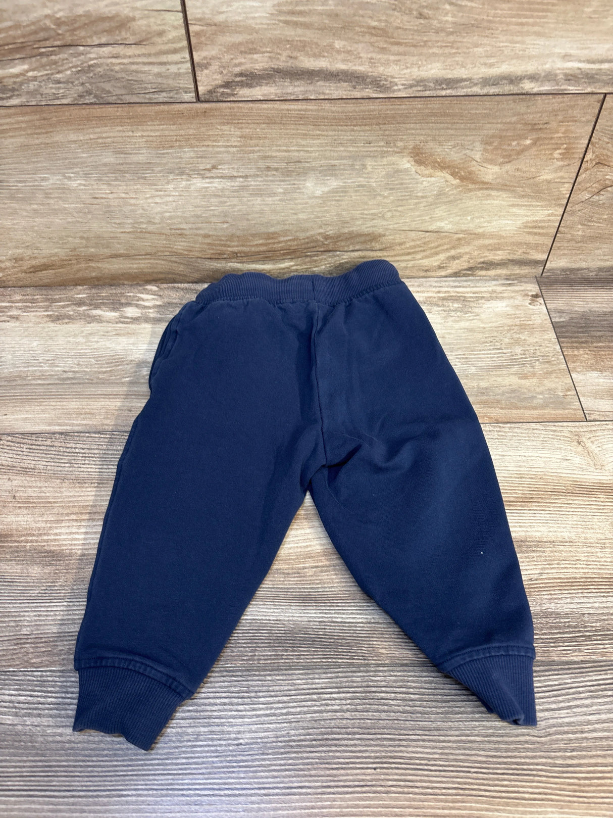 Navy blue toddler joggers with elastic waist and cuffs, laid flat on wood floor