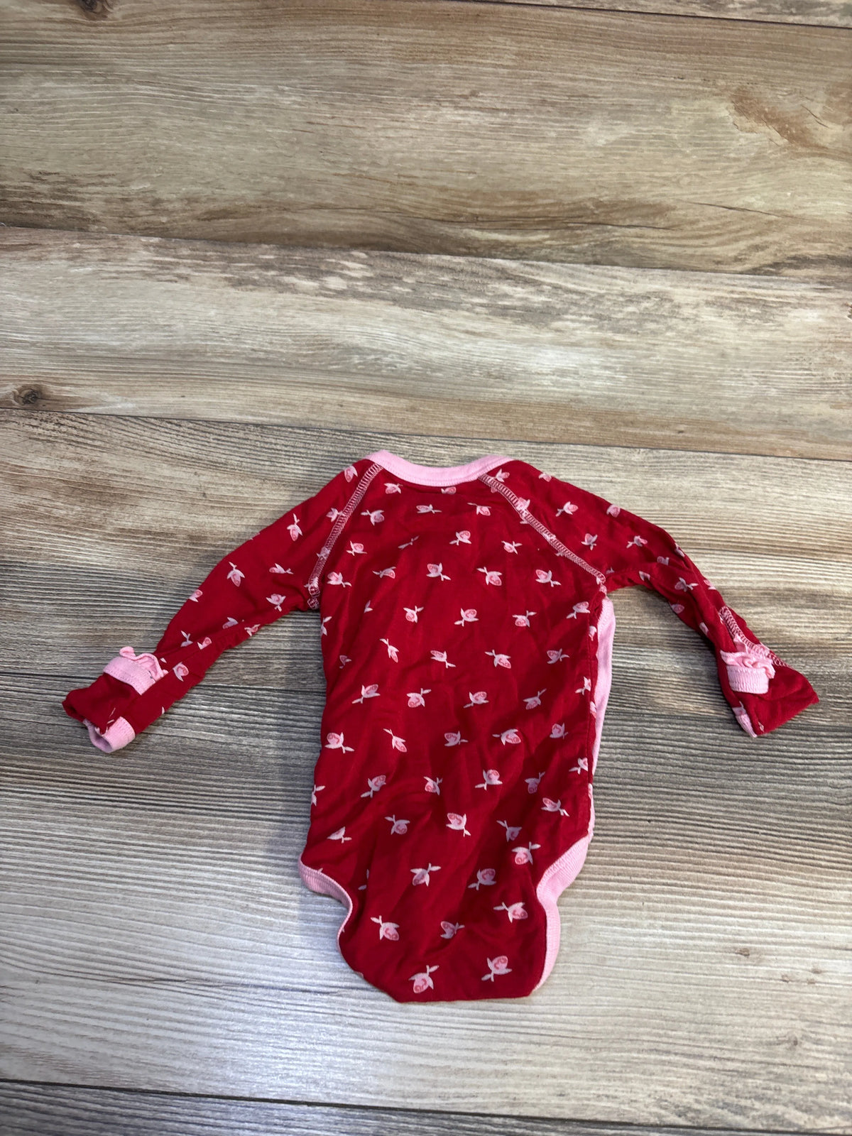 Front view of red Kickee Pants bamboo long sleeve kimono bodysuit with pink floral print and trim on a wood-grain background
