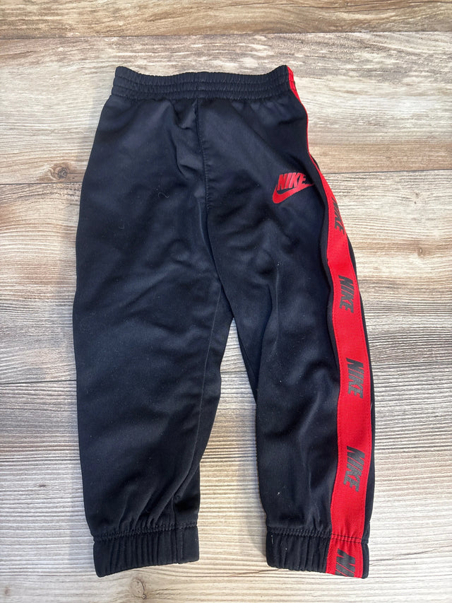 Black Nike kids track pants with red side stripes and logo, elastic waist and cuffs