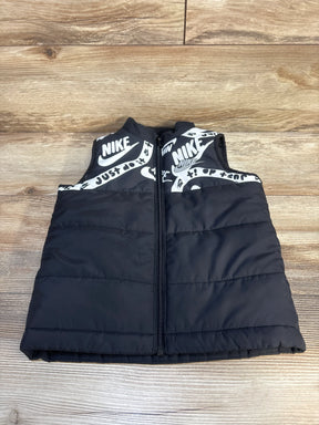 Kids black puffer vest with zipper and white graphic logo print, displayed on wood floor
