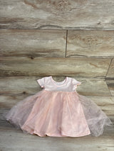 Flat lay of pink tulle baby dress showcasing glitter heart tulle skirt and short-sleeve bodice on wood floor