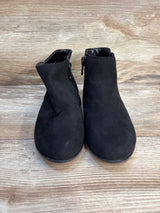 Pair of black suede children's ankle boots with side zippers on a wooden floor