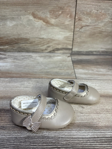 Front three-quarter view of Mayoral toddler Mary Jane shoes in tan showcasing scalloped trim, bow detail and polka dot lining on wood grain background