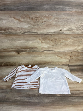Two long sleeve kids shirts, one brown striped and one plain white, on wood background