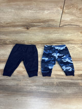 Flat lay of baby pull-on pants 2pk showcasing solid navy and blue camo prints with elastic waistbands on wood plank floor