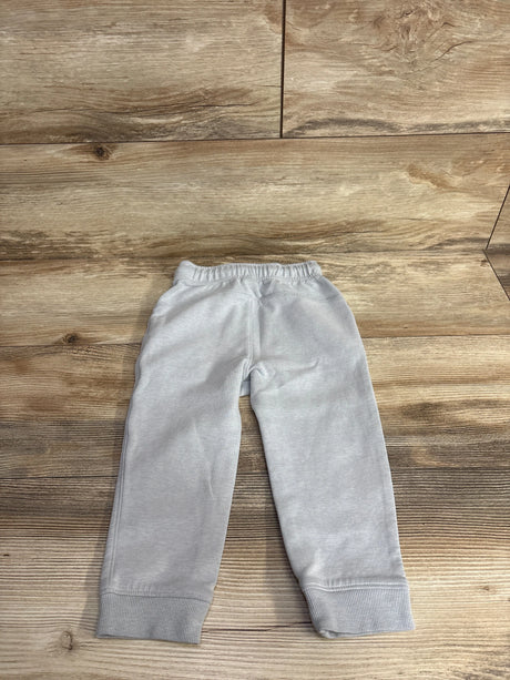 Light grey children's sweatpants with elastic waistband and cuffs on wood background