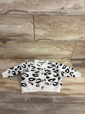 Baby cardigan with black and white animal print pattern and wooden buttons on wood floor