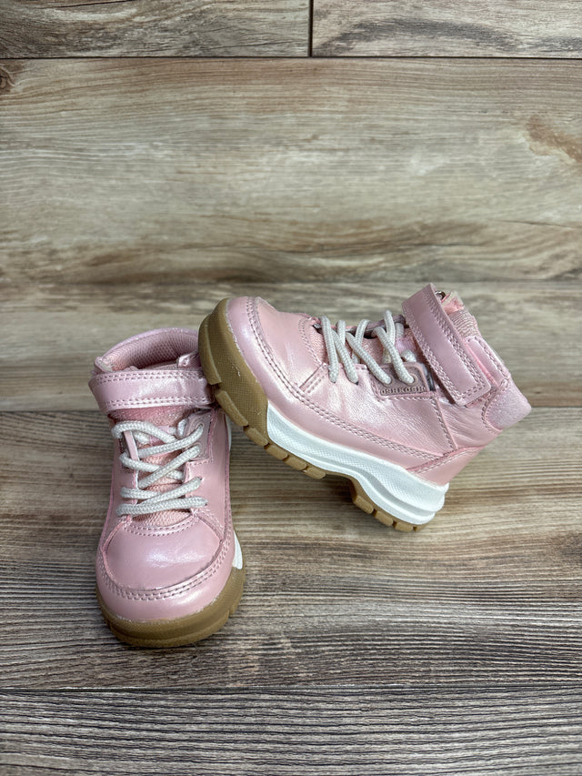 Pair of pink toddler boots with white laces and brown soles on wooden floor