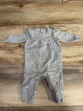 Grey baby onesie with star patterns and snap buttons on wooden floor