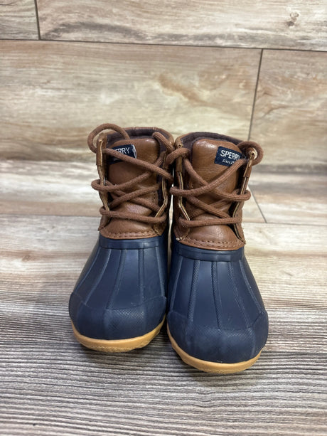 Front view of Sperry Port Alpine waterproof duck boots with navy lowers, brown leather uppers, and tan soles on wood floor
