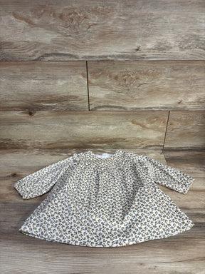 Flat lay of newborn cream velvet long-sleeve floral dress showcasing ruffled yoke and gathered skirt on wood background