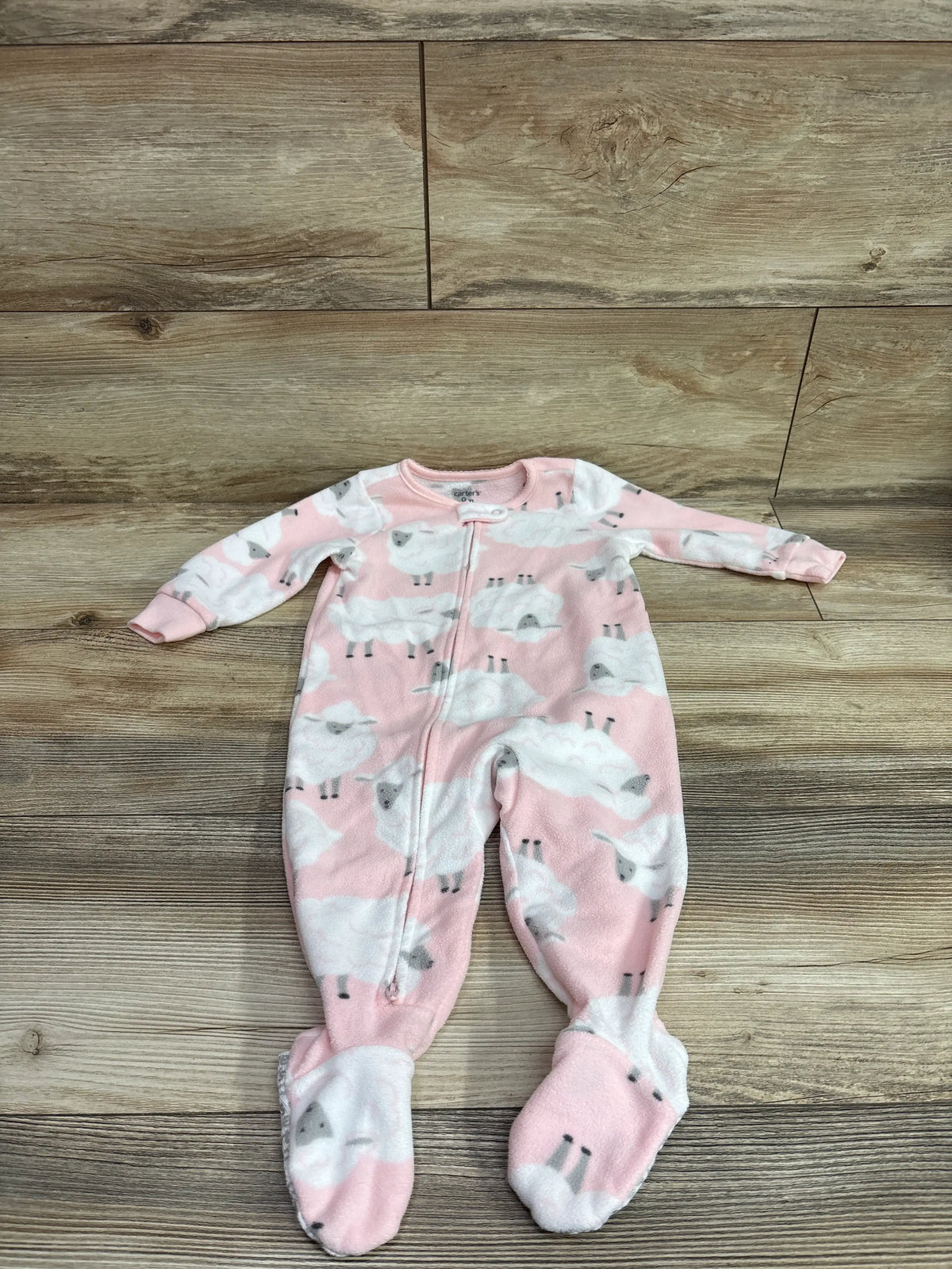 Pink Carter's blanket sleeper for babies with white sheep print on wood background