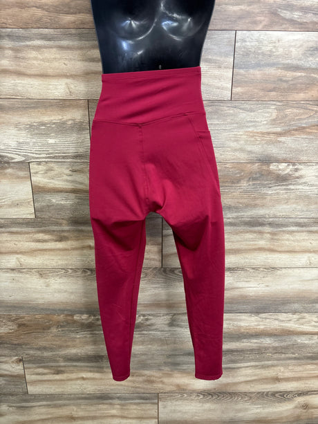 Front view of red maternity athletic leggings with high-rise belly panel and tapered ankles on mannequin with wood background
