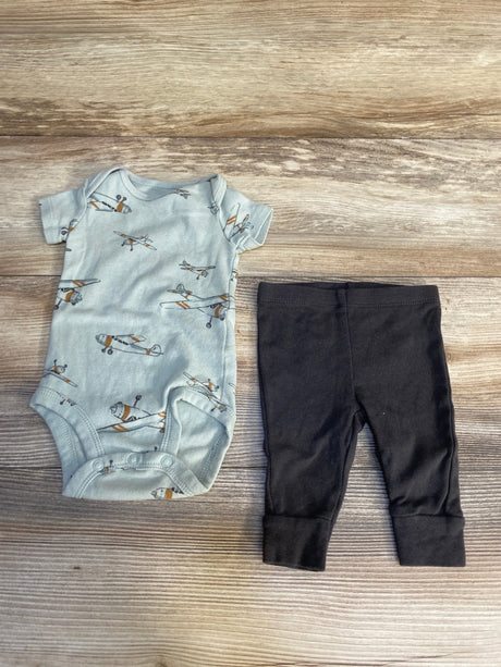 Baby boy airplane print bodysuit and black pants set on wooden background