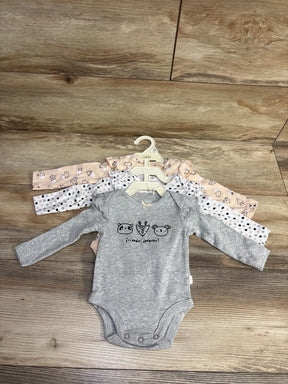 Three long-sleeve baby onesies on hangers with cute animal and polka dot patterns, laid on wooden floor
