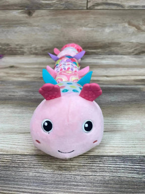 Front view of pink Sumobaby musical caterpillar plush with textured silicone feet and colorful patterned segments on wood background