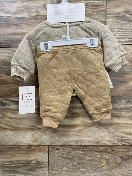 Quilted beige and tan baby outfit set with pants and long sleeve top on wooden background