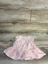 Flat lay of pink floral baby dress showcasing puff sleeves and ruffled hem on light wood background