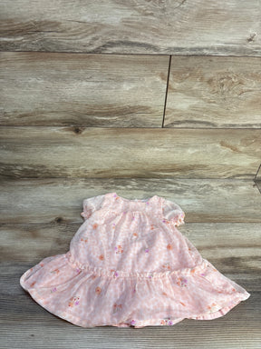 Flat lay of pink floral baby dress showcasing puff sleeves and ruffled hem on light wood background