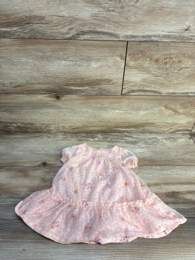 Flat lay of pink floral baby dress showcasing puff sleeves and ruffled hem on light wood background