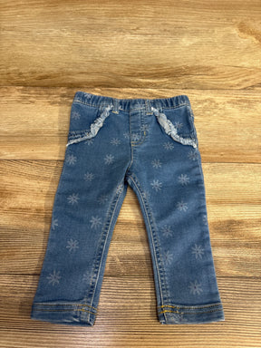 Toddler blue denim jeans with floral print and frayed pocket trim on wooden surface