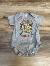 Gray baby onesie with D20 dice, swords, and 'Level 1 Human' graphic, laid on wood background