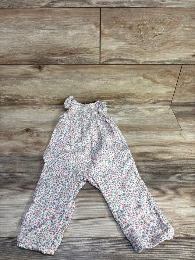 Flat lay of Little Planet white smocked floral jumpsuit, 12m, showing smocked bodice and ruffled sleeves on wood floor