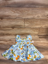 Blue baby dress with orange & palm tree print, button front, laid on wood floor