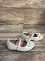 Side view of white Sugar Nira toddler flats showcasing glitter bow and single strap on wood background