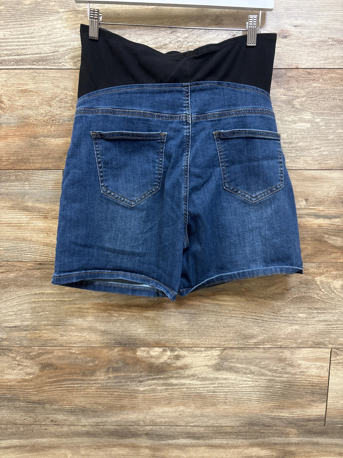 Rear view of Me n Mommy To Be blue maternity full panel denim shorts on a wooden background