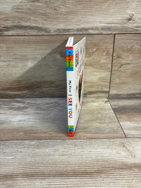 Side view of My First I See You board book showcasing colorful spine text and round mirror cutout with light wood plank background