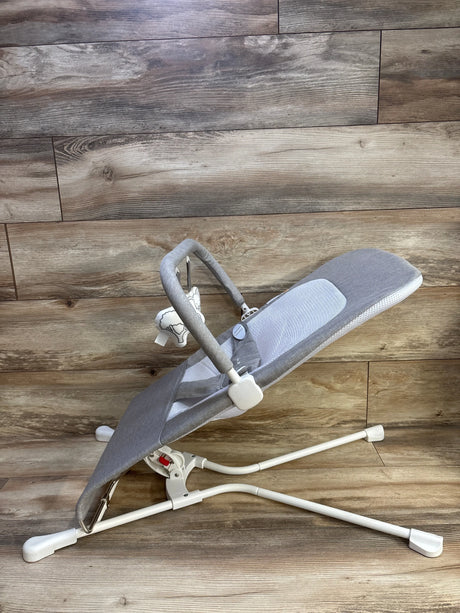 Side view of Baby Delight Highland bouncer showing pebble grey fabric, mesh seat, toy bar with plush, white frame