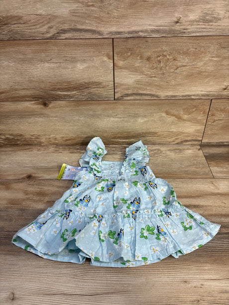 Top down view of light blue Bluey floral baby dress size 12 months showcasing Swiss dot texture, ruffled skirt on wood floor background