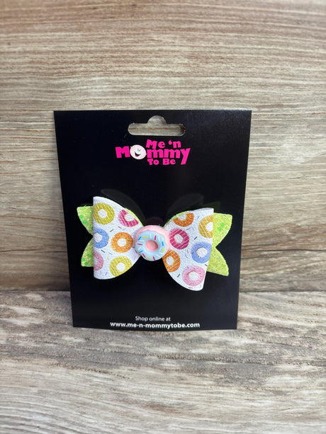 Front view of donut hair bow with multicolor donut print, pink sprinkle center, and green glitter back on black card
