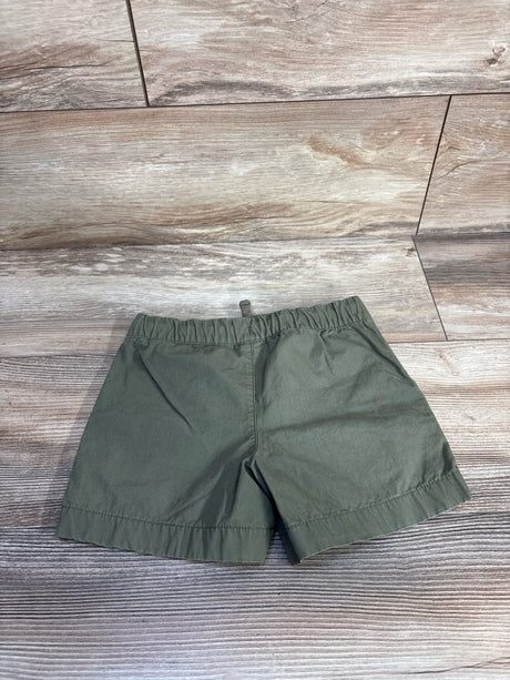 Flat-lay of Carter's green toddler drawstring shorts showing elastic waistband and straight hem on light wood background