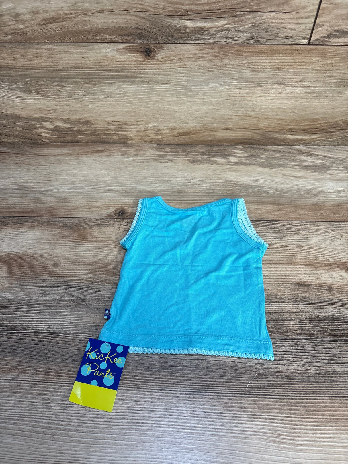 Blue sleeveless toddler tank top with lace trim, kids clothing on wood floor, Kickee Pants tag
