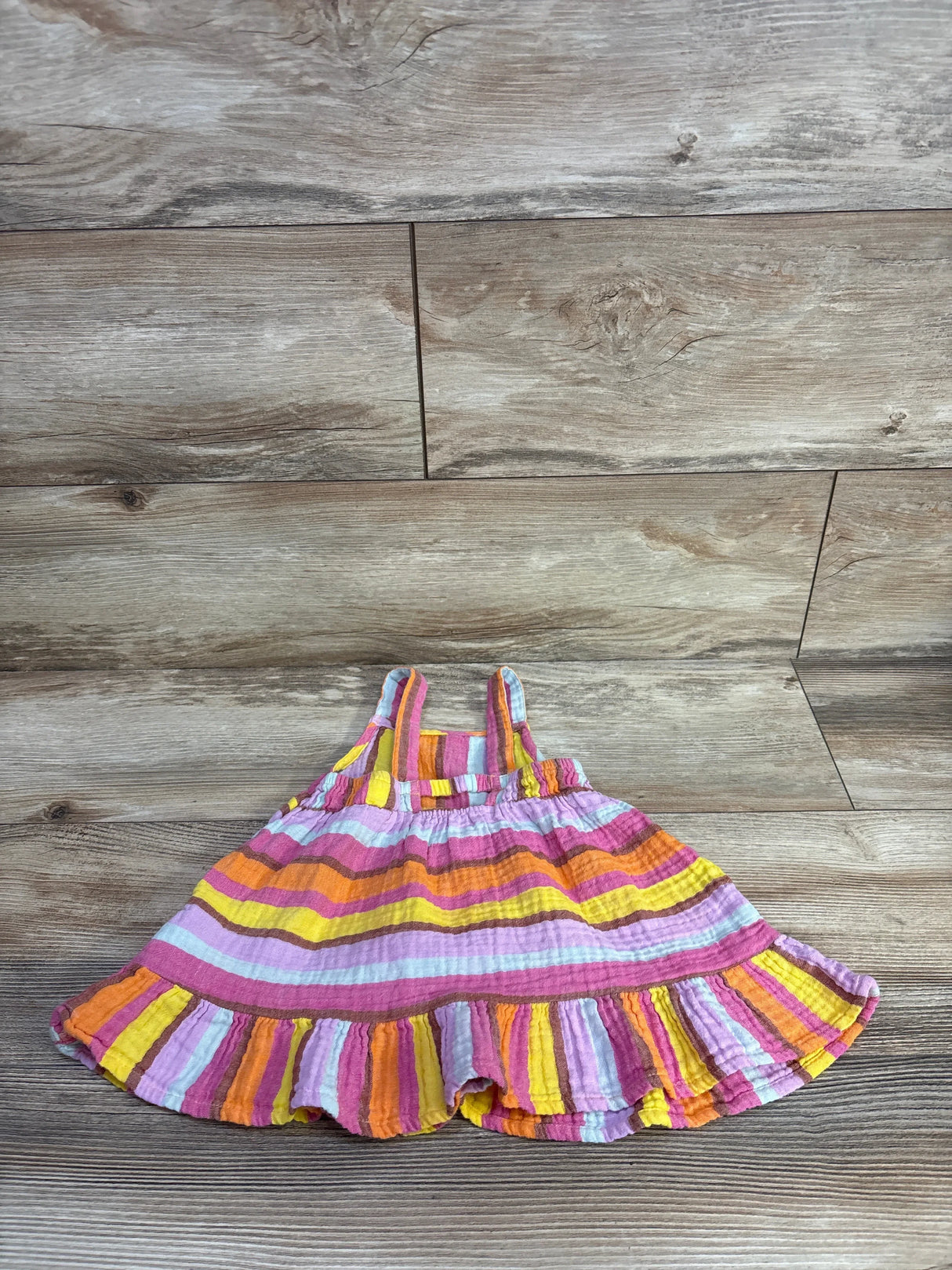 Flat lay of Cat and Jack muslin tank dress (18M) showing multicolor stripes and ruffle hem on wood floor background