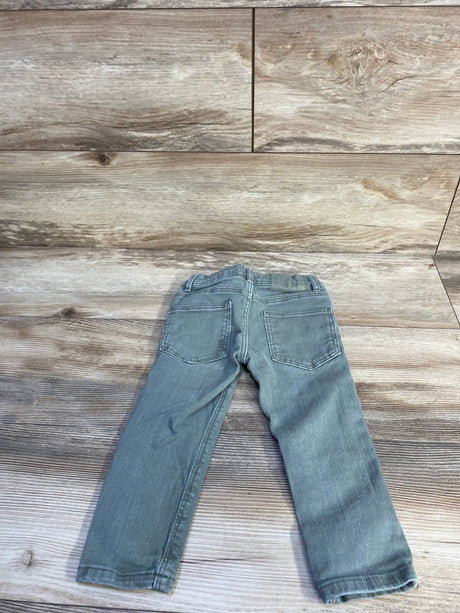Back view of toddler green Zara slim denim jeans showing rear pockets and elastic waistband on light wood background