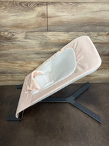 Side view of Baby Delight Alpine Deluxe bouncer in pale pink with white mesh seat, head support, and black X-shaped base