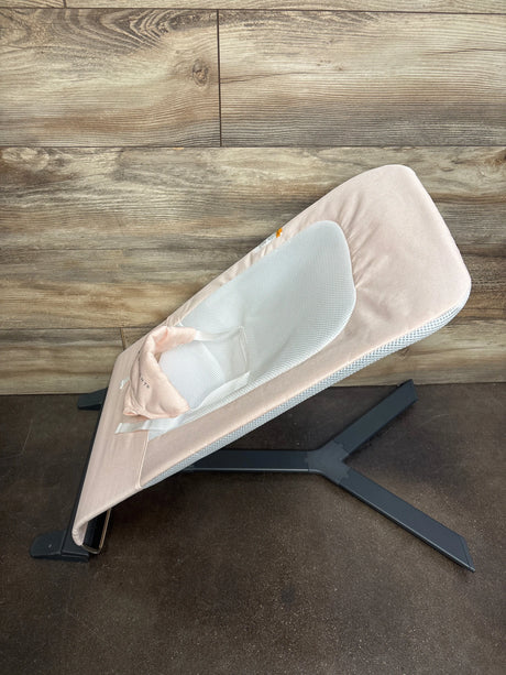 Side view of Baby Delight Alpine Deluxe bouncer in pale pink with white mesh seat, head support, and black X-shaped base
